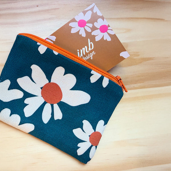 Floral pouch with orange zipper on a wooden surface, featuring 'imb design' card.