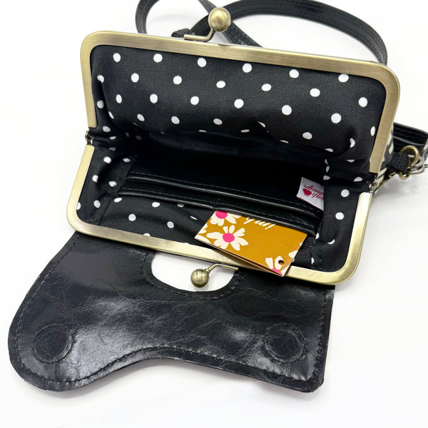 Interior of Audrey Wallet Clutch. Features an interior wallet with pockets to store money and credit cards. Lining is a black and white polka dot fabric.