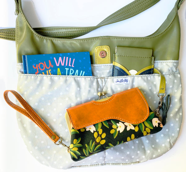 Lining detail photo of Twyla Tote Bag. Featuring four interior slip pockets and a key snap. Magnetic closure at the top center. Lining is cotton canvas polka dots. Featuring a grey background with white dots.